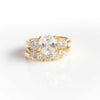 CUSHION CUT ENGAGEMENT RING WITH SIDE DIAMONDS AND FIVE STONE CURVED BAND IN YELLOW GOLD PLATING.